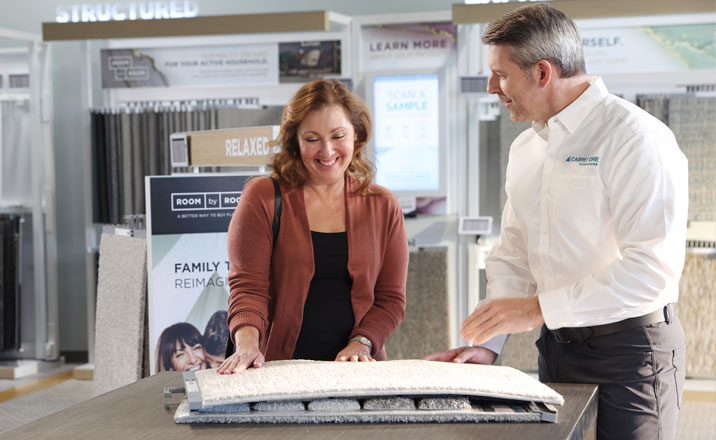 Customer and sales associate discussing flooring options at Ramey Floor & Home store, showcasing flooring samples and interior design solutions.