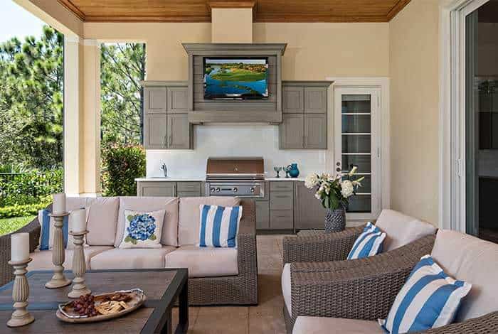 Outdoor kitchen with TV, seating, and cabinetry for relaxing and entertaining.