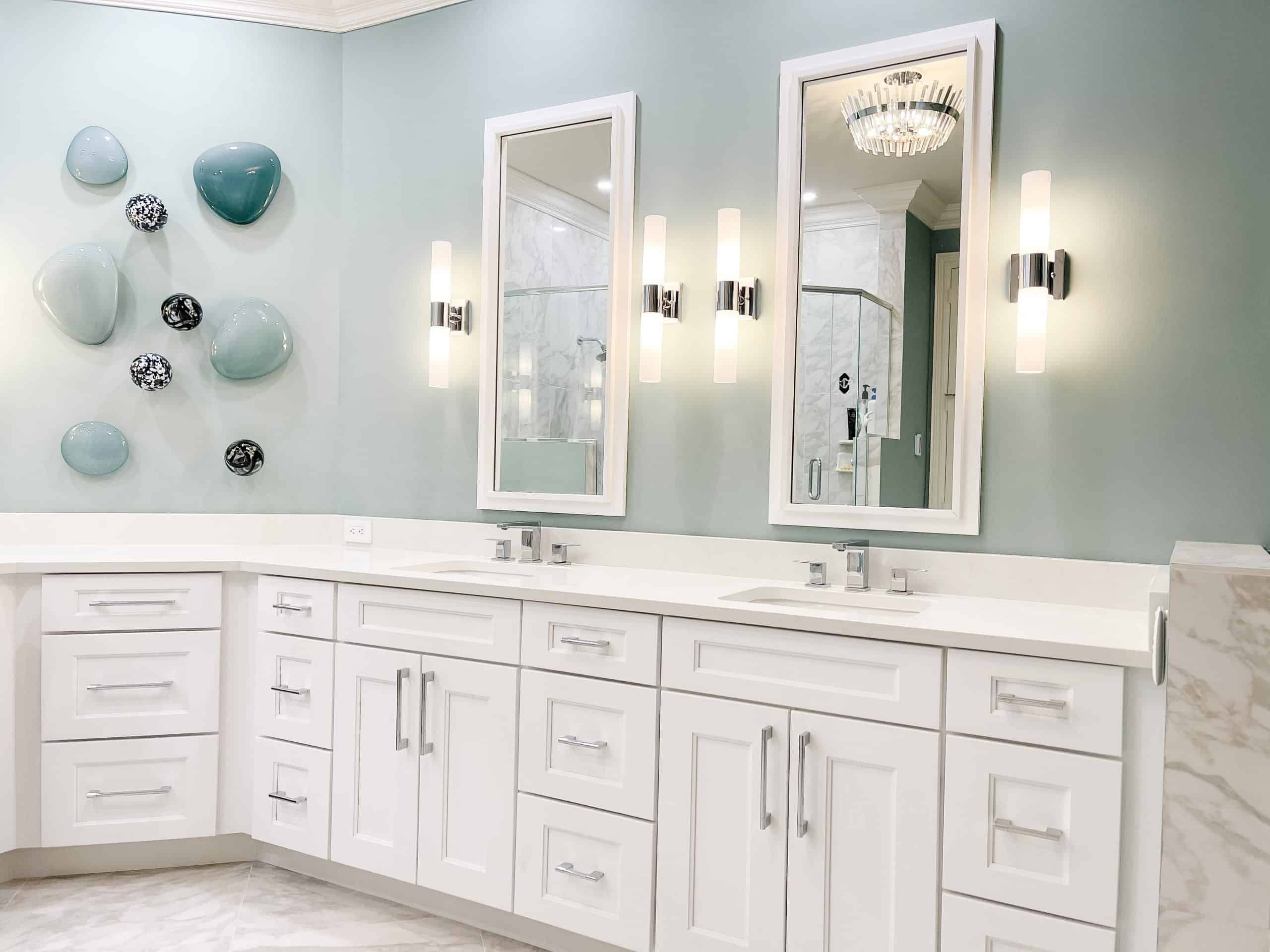 Bright bathroom with double mirrors, wall sconces, and white cabinetry.
