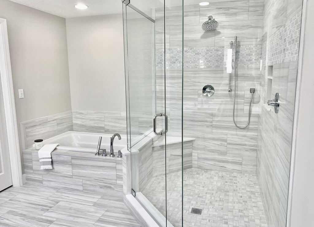Luxurious bathroom featuring a spacious glass shower and a built-in soaking tub with marble tiles and sleek fixtures.