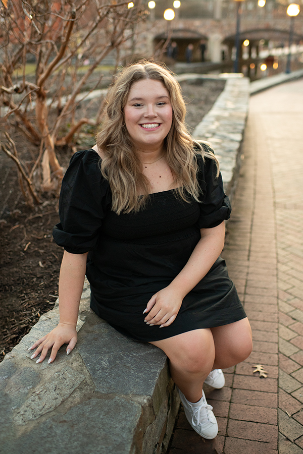 High school senior in a black dress posing by Carroll Creek in Frederick Maryland during outdoor senior portraits