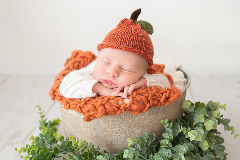 newborn in vintage bucket with pumpkin hat
