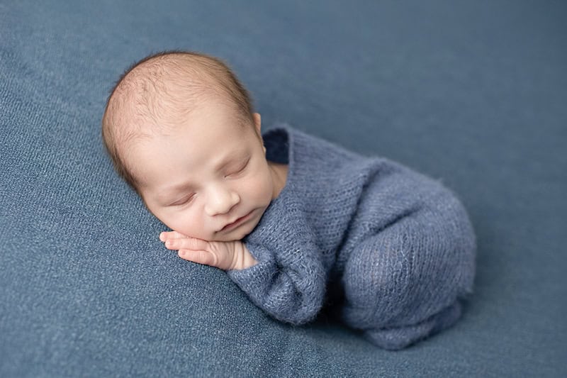 Newborn baby boy in blue romper at Frederick MD newborn photography studio