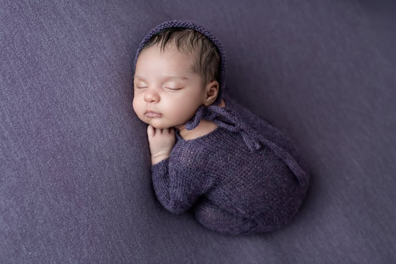 gorgeous baby in purple romper on a matching backdrop at jennifer riley photography