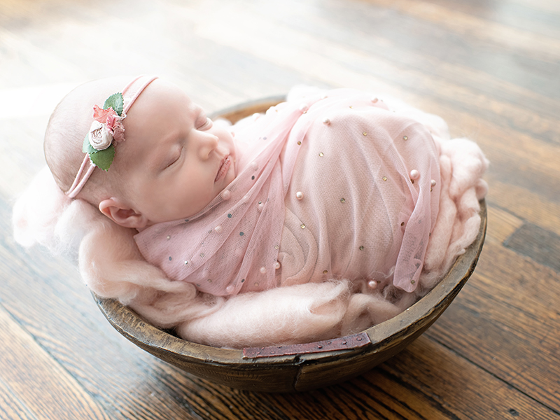 baby in tiny vintage bowl in pink beaded swaddle
