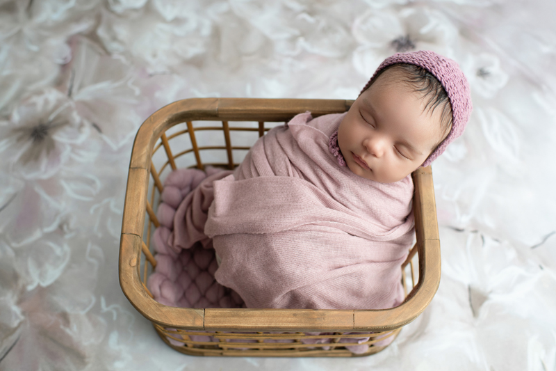 baby in neutral wooden prop in pink with hat