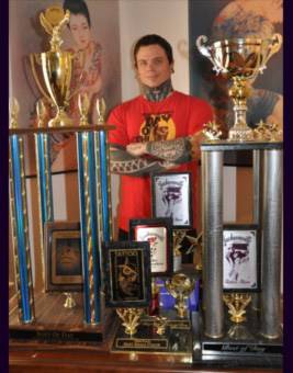 Jesse Britten Tattoo, St. Augustine, FL Tattooed man surrounded by trophies and awards.