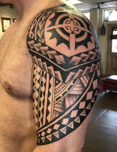 Jesse Britten Tattoo, St Augustine FL. Polynesian tribal tattoo sleeve on a man's upper arm, featuring bold black geometric patterns and shapes.