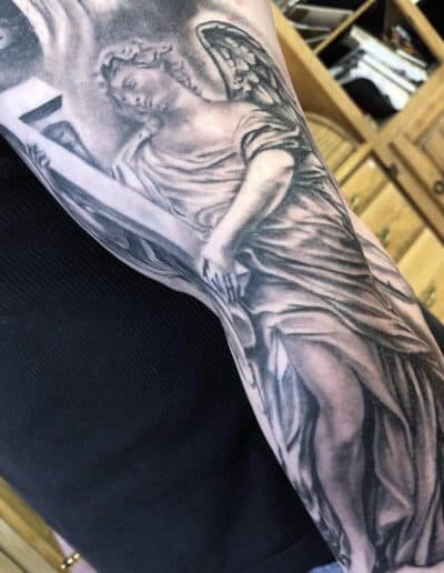 Jesse Britten Tattoo, St. Augustine, FL Angel tattoo on arm holding a cross with detailed shading