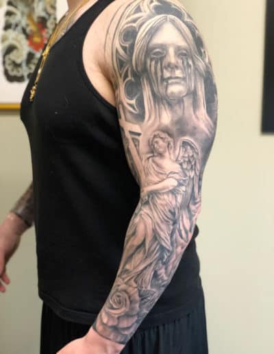Jesse Britten Tattoo, St. Augustine, FL - Detailed black and gray tattoo sleeve featuring an angel, a cross, and a weeping woman.