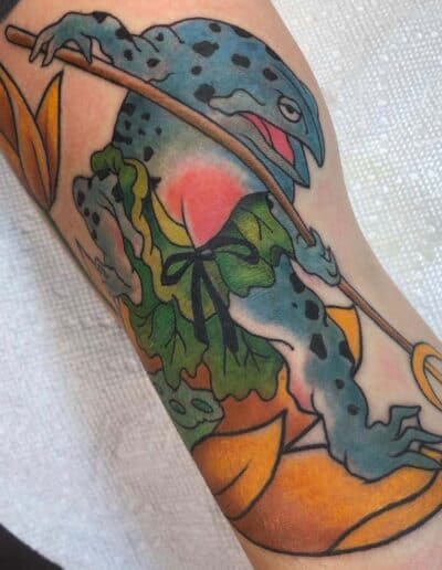 Jesse Britten Tattoo, St. Augustine, FL Blue frog tattoo with a spear, sitting on a lotus flower. Japanese tattoo art.