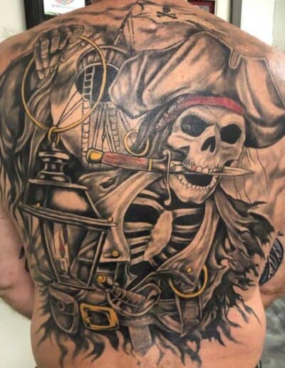 Jesse Britten Tattoo, St. Augustine, FL Pirate skeleton back tattoo featuring a skull with a knife, lantern, and pirate hat.