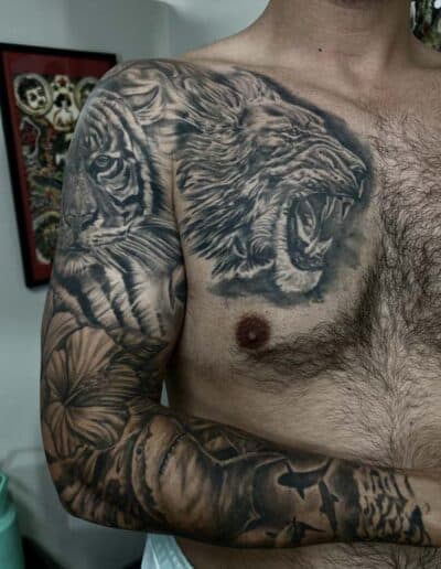 Detailed tiger and lion tattoo on man's arm and chest.