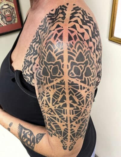 Bold tribal-style tattoo sleeve on upper arm in St Augustine, Florida.