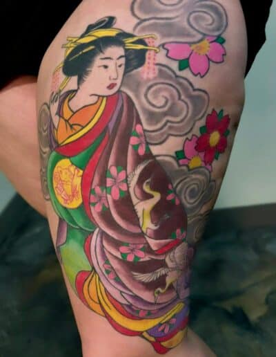 Geisha tattoo with cherry blossoms and clouds on a person's thigh in St Augustine, Florida.