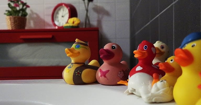 Colorful rubber ducks add fun to a modern bathroom setting with red accents.