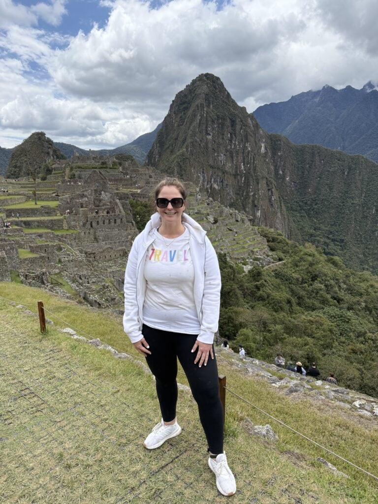 Travel enthusiast visiting Machu Picchu in Peru, exploring ancient Incan ruins with stunning mountain views, showcasing adventure travel and cultural exploration.