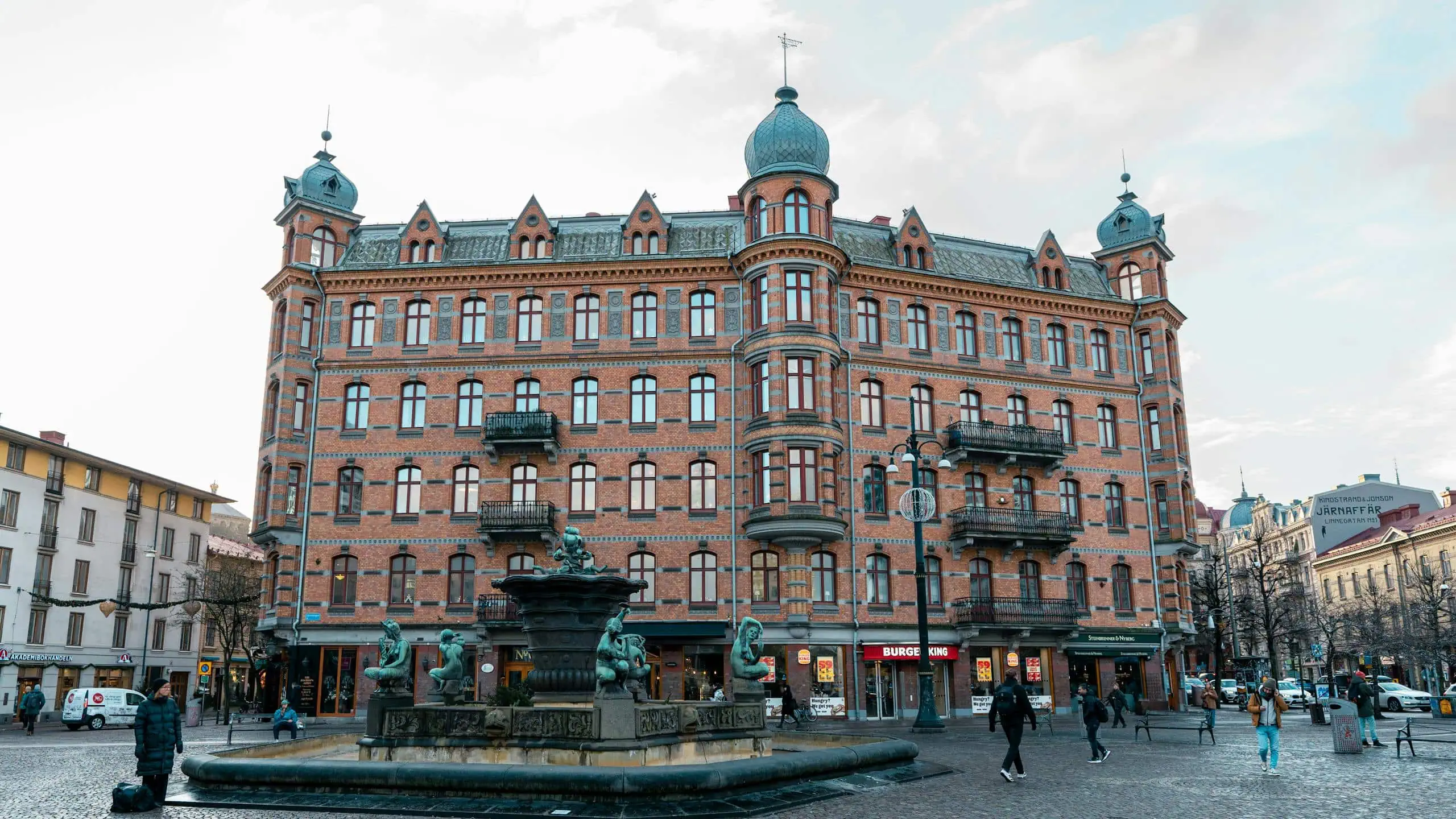 Historic Hotel Royal Palace in Stockholm featuring classic architecture and a central fountain, surrounded by city streets and pedestrians.