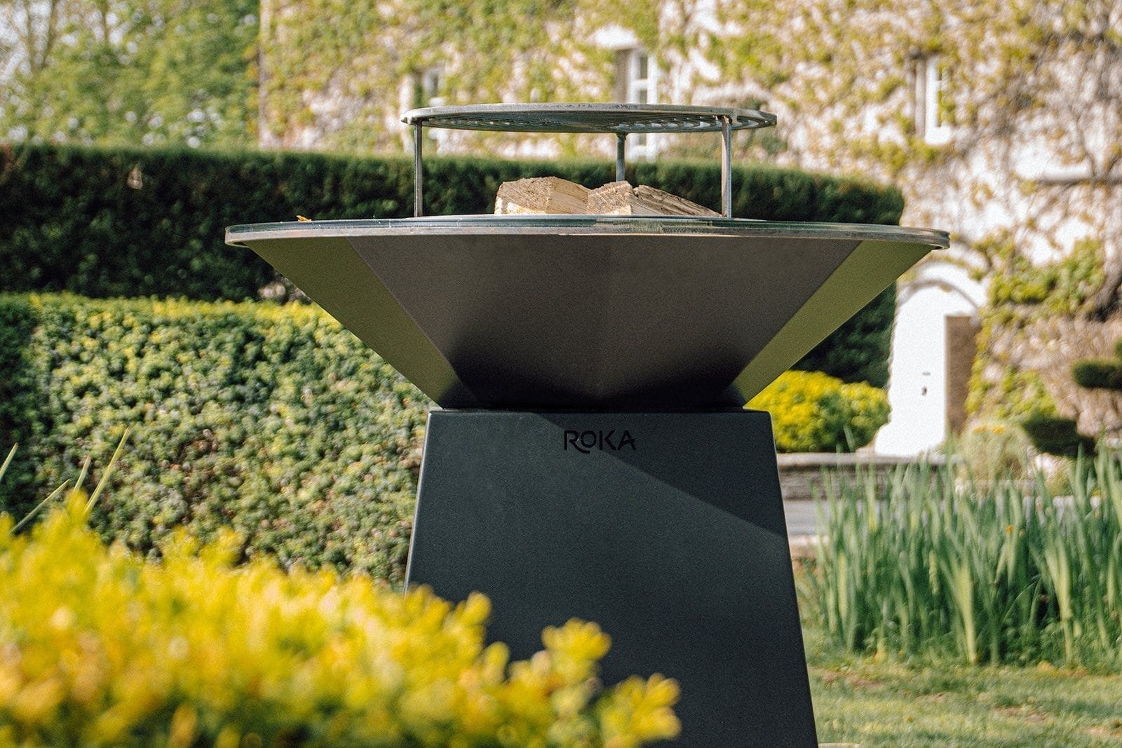 Brasero design Roka disposé en extérieur dans un jardin
