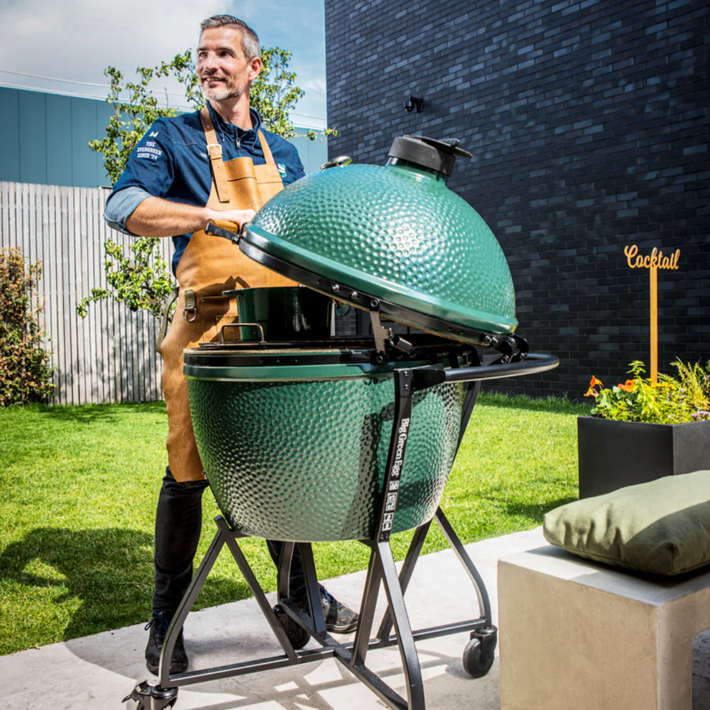 Homme cuisinant avec un kamado XXL Big Green Egg XXL professionel sur chariot
