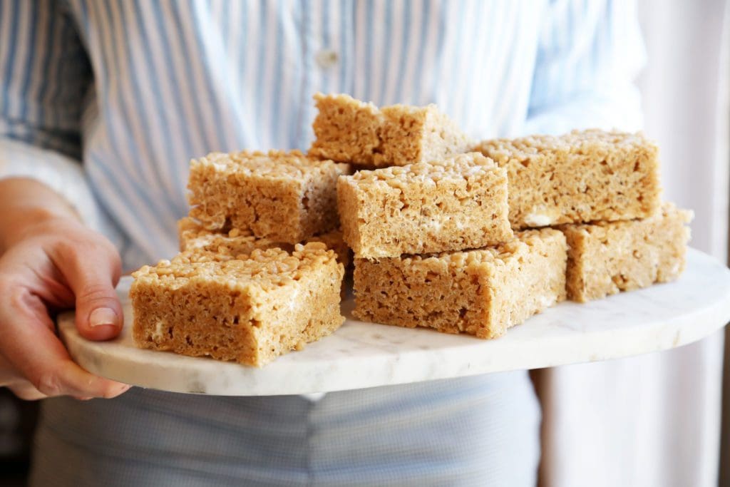 Joy the Baker holding krispie treats stacked on a platter.
