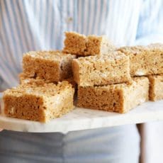Joy the Baker holding krispie treats stacked on a platter.