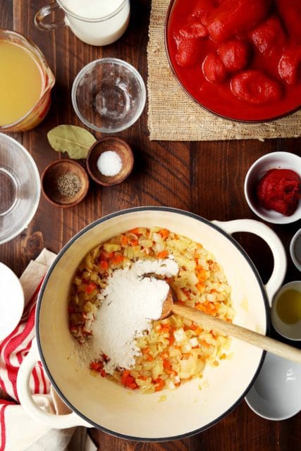 A few tablespoons of flour in browned vegetables for creamy tomato soup recipe.
