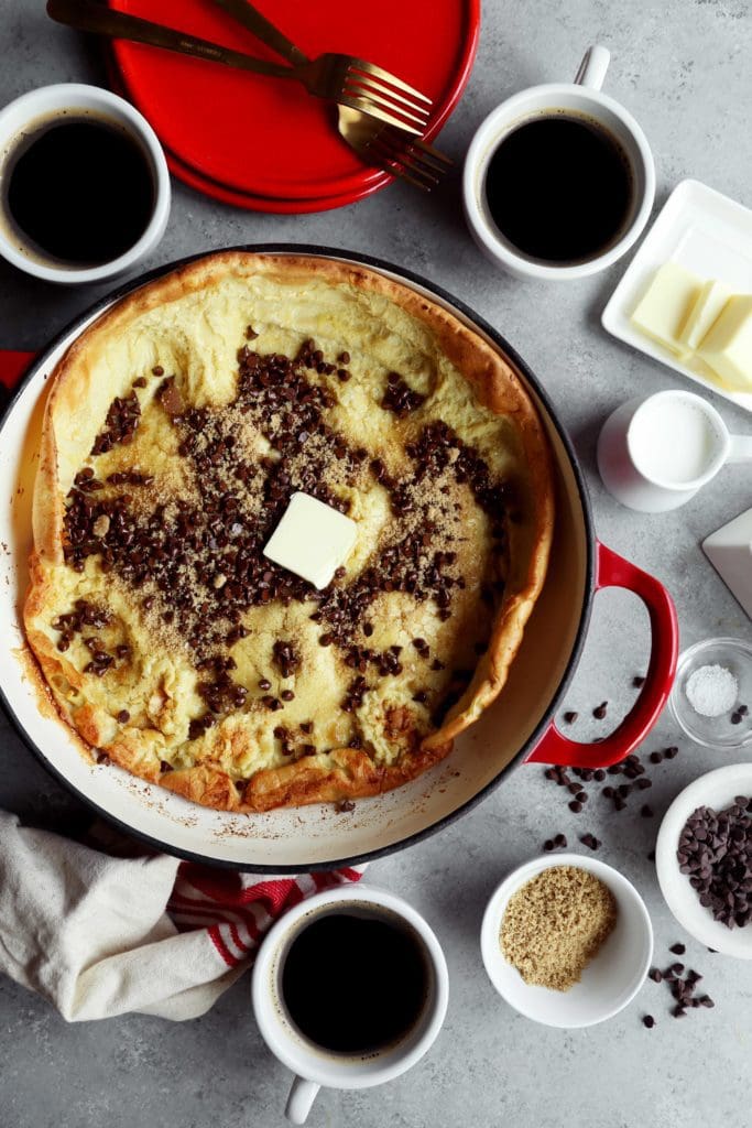 Freshly cooked Dutch baby sprinkled with chocolate chips and brown sugar