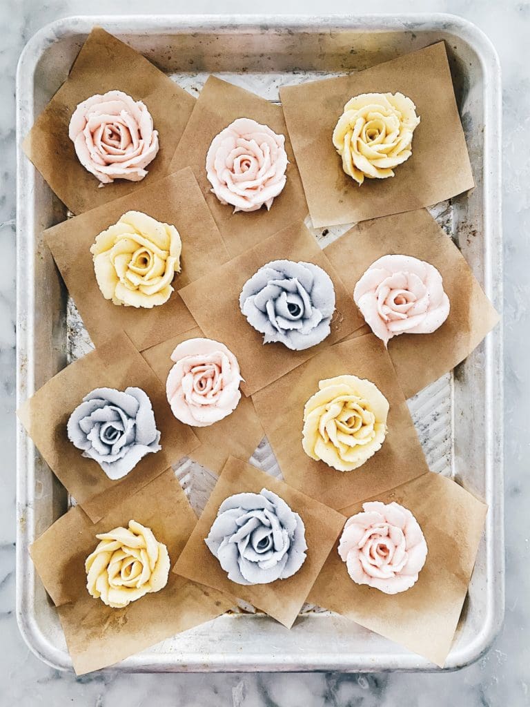 pastel colored buttercream roses on a baking sheet