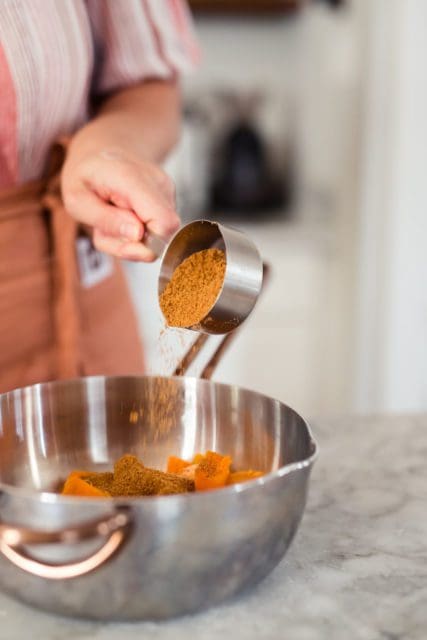 Adding brown sugar to boiled sweet potatoes.