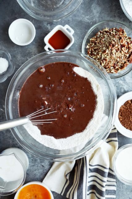 Melted chocolate stirred into a bowl with flour and sugar for Texas Sheet Cake.