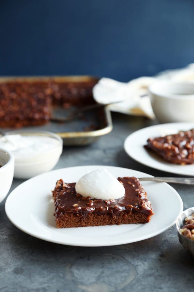 A slice of Texas Sheet Cake on a plate dolloped with whipped cream