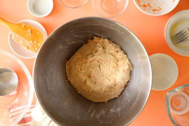 Mixed gluten free carrot cake cinnamon roll dough in a mixing bowl.