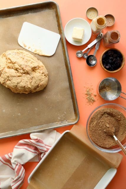 Risen cinnamon roll dough on a greased piece of parchment paper.