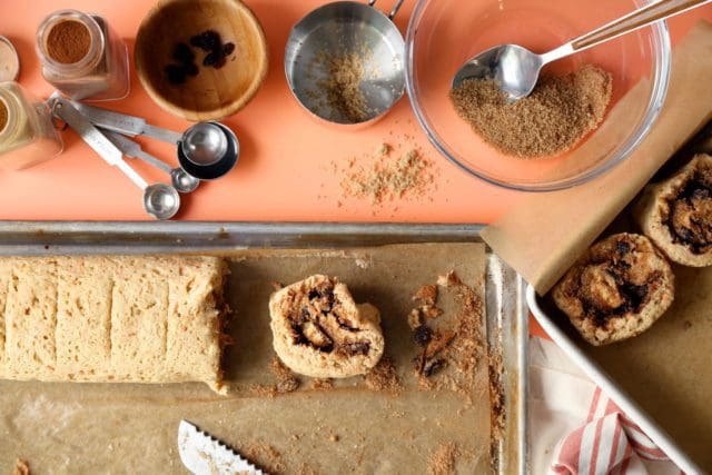 Rolled and chilled cinnamon rolls on a pan being sliced