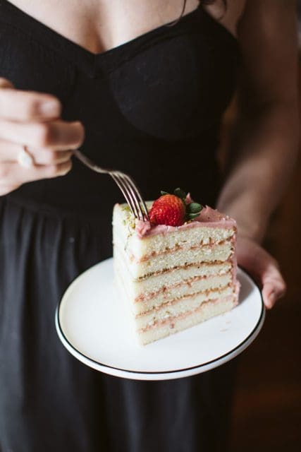 Slice of strawberry and pistachio doberge cake on a place with fork.
