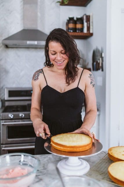 Using a rotating cake stand to slice vanilla cake layer in half.