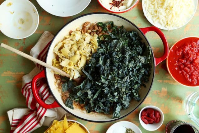 Kale, sausage, and artichoke hearts sautéing in a cast iron skillet
