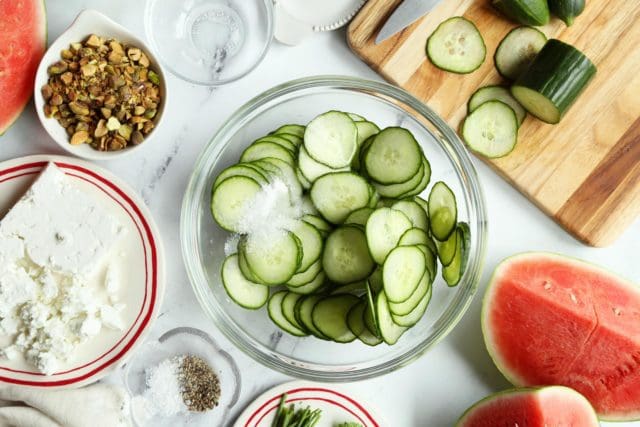 A bowl of thinly sliced cucumbers with salt and vinegar