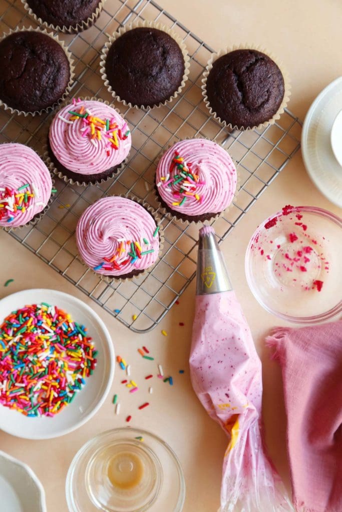 Piping bag and chocolate cupcakes on wire rack.