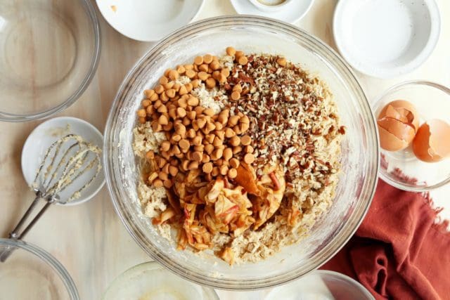 Cookie dough with dried apples, pecans, and butterscotch chips in a bowl.