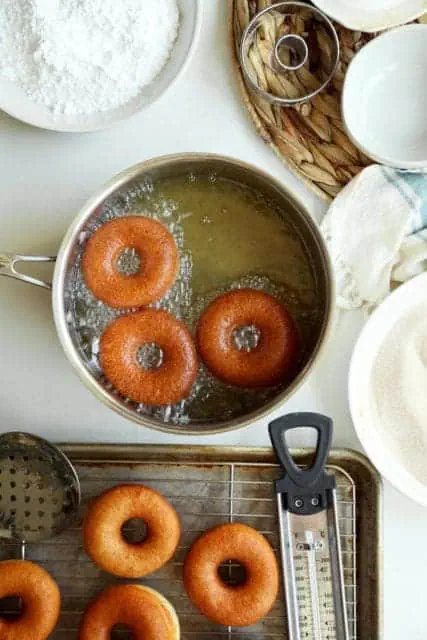 Yeasted Doughnuts frying to golden in hot oil.