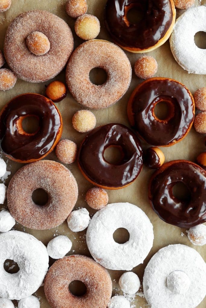 Fried doughnut covered in powdered sugar cinnamon sugar, and chocolate glaze.