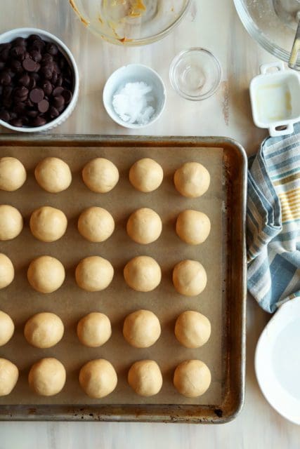 Rolled balls of dough on a parchment lined sheet.
