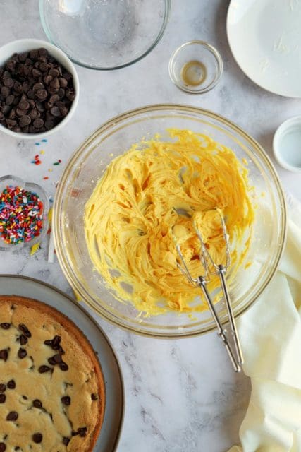 Buttercream tinted yellow in medium bowl.