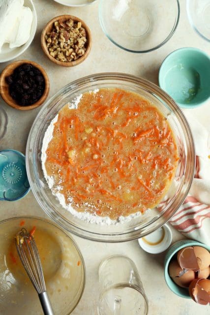 Wet and dry ingredients of carrot cake recipe combined in large bowl.