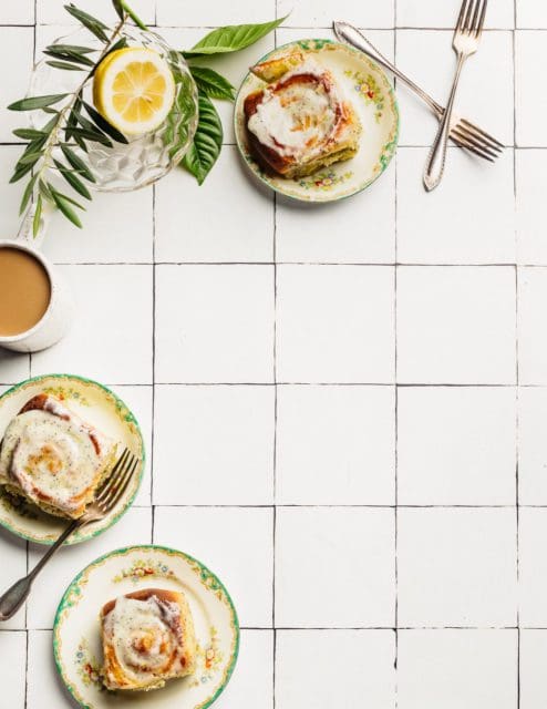 Small plates with lemon poppy seed rolls and a cup of coffee.