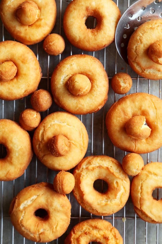 Fried old fashioned doughnuts on a cooling rack