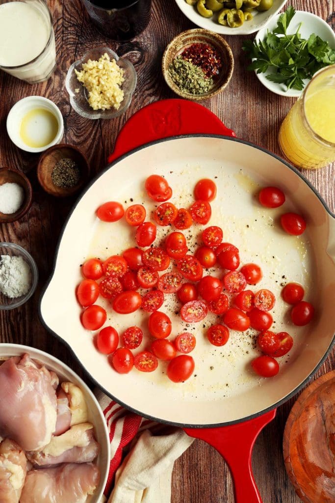 Cherry tomatoes halved in a skillet with salt and pepper for roasting.