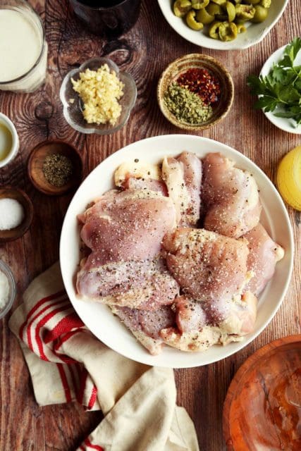 Chicken thighs seasoned in a bowl.